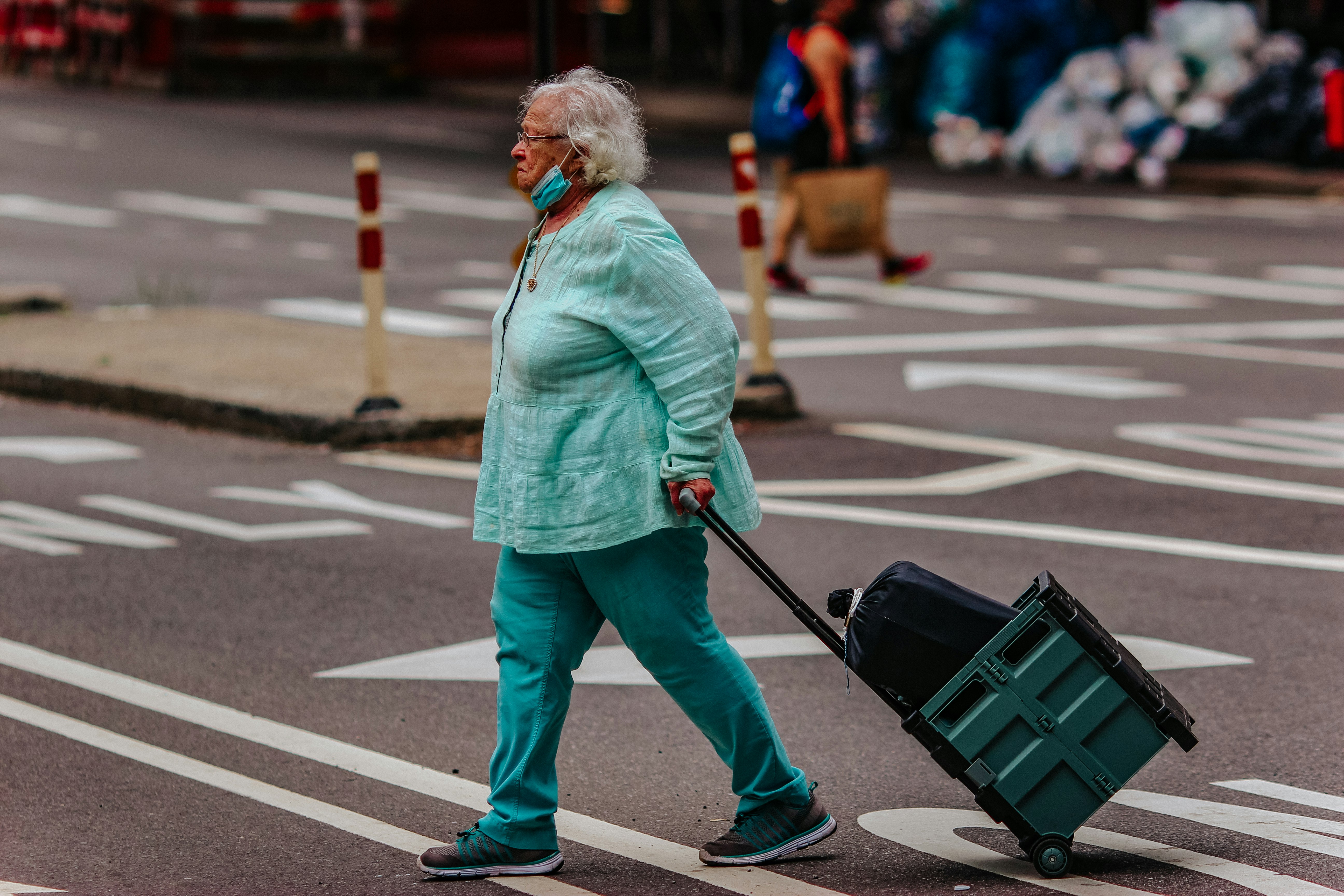 woman in green jacket and gray pants walking on pedestrian lane during daytime